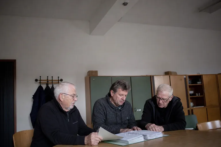 Vereinsfunktionäre besprechen Zuständigkeiten anhand einer Terminakte