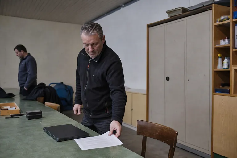 Standaufsicht sortiert Schießnachweise und Laptop auf einem Tisch im Schützenhaus